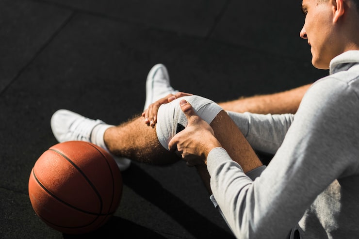 Jugador de baloncesto colocándose un vendaje en la rodilla tras una lesión, atendida en la Unidad de Traumatología Deportiva en Lima de Novotrauma