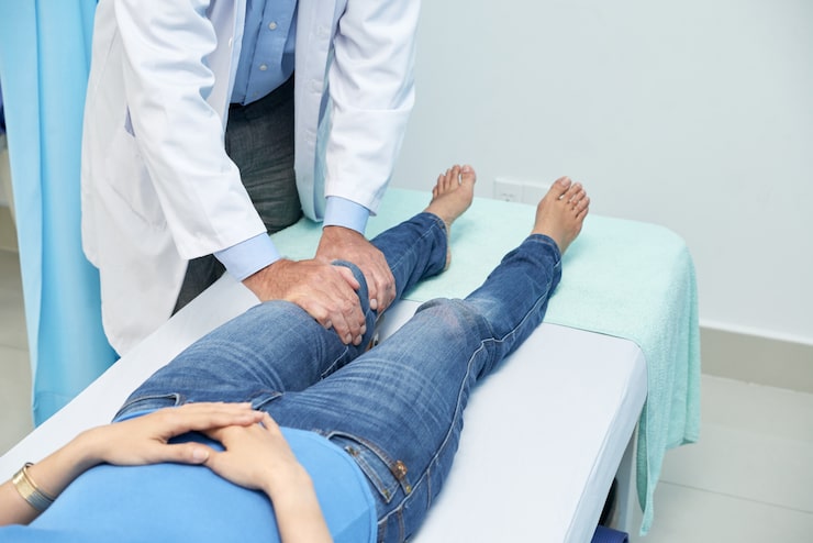 Traumatólogo evaluando la rodilla de un paciente recostado en la camilla durante una consulta en la Unidad de Rodilla de Novotrauma