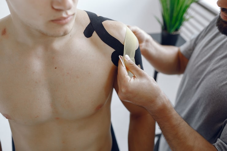 Médico aplicando kinesiotape en el hombro de un deportista en la Unidad de Hombro de Novotrauma, Lima
