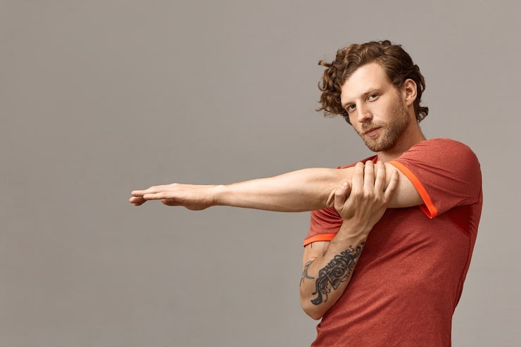 Deportista estirando los músculos del brazo para calentar antes de entrenar, una forma de prevenir lesiones del codo