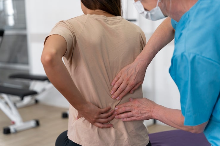 Asistente médico ayudando a un paciente con ejercicios de fisioterapia para la espalda en Novotrauma