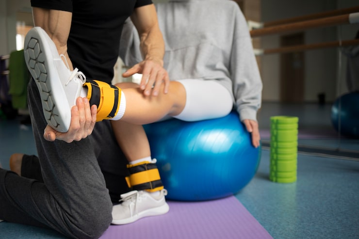 Paciente realizando rehabilitación física con ayuda de terapeutas tras una lesión deportiva