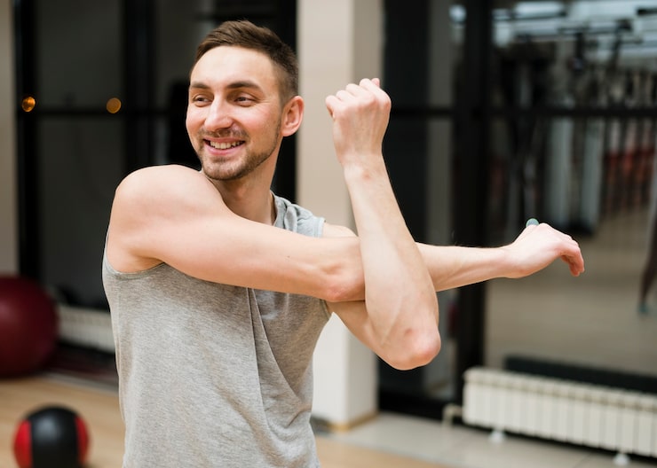 Hombre estirando las piernas y el cuerpo en el gimnasio como parte de la prevención de lesiones
